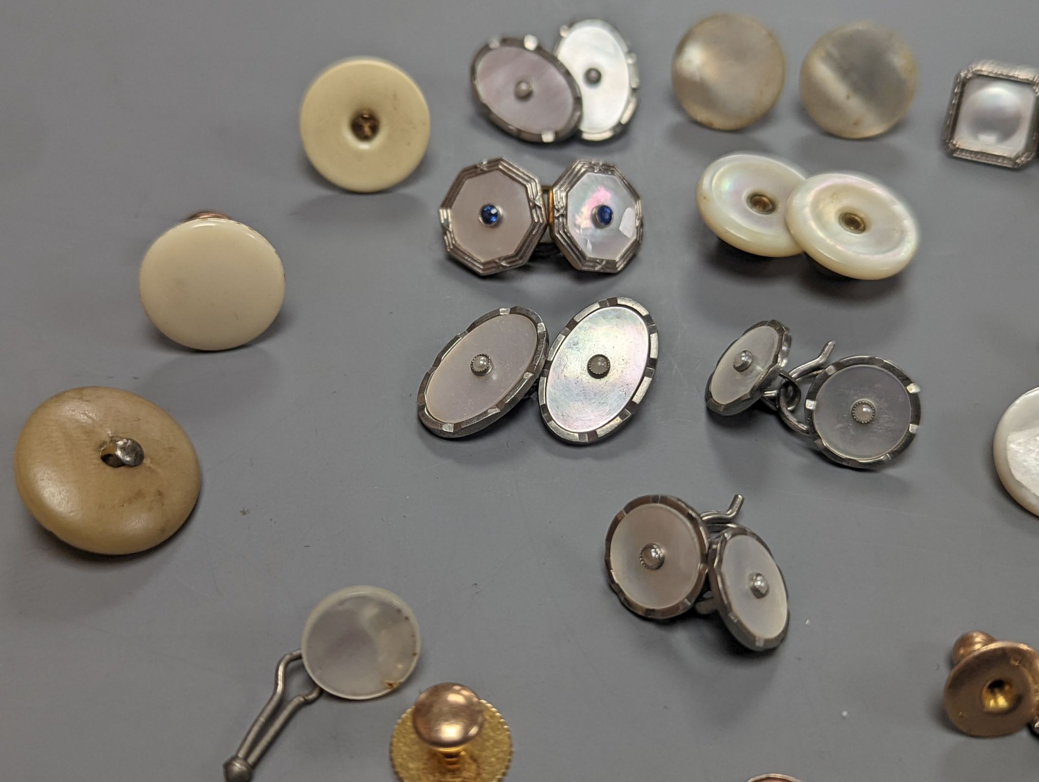 Two pairs of 18ct and mother of pearl cufflinks, one set with sapphires, both with gilt metal associated links, together with a quantity of base metal buttons, cufflinks, studs, etc.